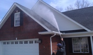 Rinsing a brick gable and gutter with a pressure washer